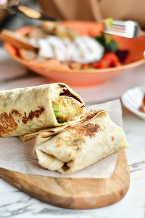 Vegetarian wrap on a wooden desk in cafe closeupの写真素材