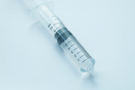syringe with clear liquid on light backgroundの写真素材