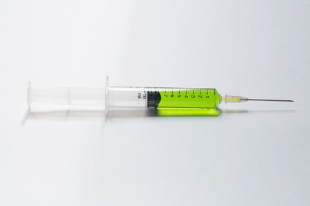 syringe with green liquid on light backgroundの写真素材