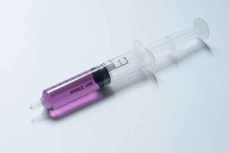 syringe with purple liquid on light backgroundの写真素材