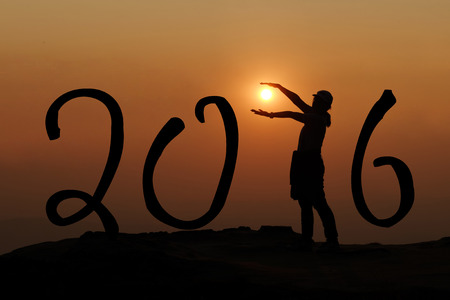 New year 2016. Silhouette of woman holding the sun on hill in sunset.の写真素材