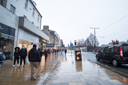 Edinburgh, United Kingdom. 17 March 2017 : People walking on the street, with car, building in background. On Princes Street, the main shopping street in Edinburghのeditorial素材