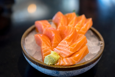 Salmon sashimi with vegetable and ice in a bowl, served in a restaurantの写真素材