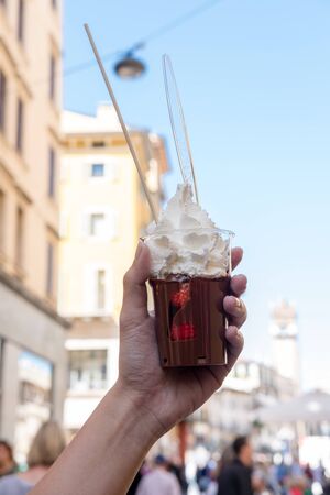 Hand holding a cup of Strawberry with chocolated and whipped creamの写真素材