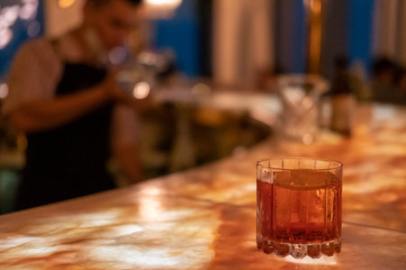 A glass of cocktail on illuminated counter barの写真素材