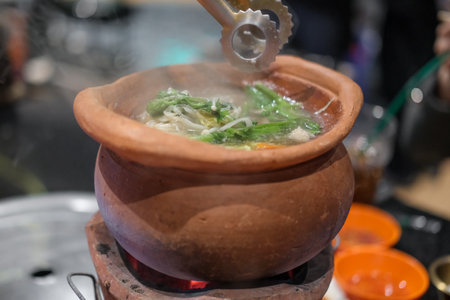 Jim Joom, Thai style of hot pot from the Northeast of Thailand contains pork, vegetable and glass noodle in clay bowlの写真素材