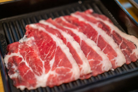Close up of sliced raw meat, ready to be cooked by hot potの写真素材