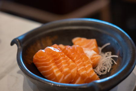 Salmon sashimi with vegetable on plate, served in a restaurantの写真素材