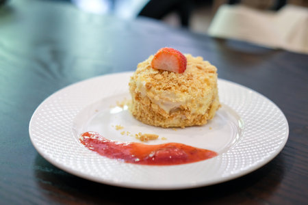 Napoleon cake, made with layers of puff with whipped cream and crumbs with Strawberry on top and sauce served on plateの写真素材