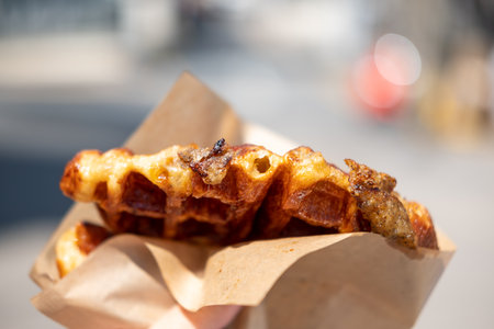 Hand holding Croffle with truffle. It is a hybrid of a croissant and waffle which is a popular...