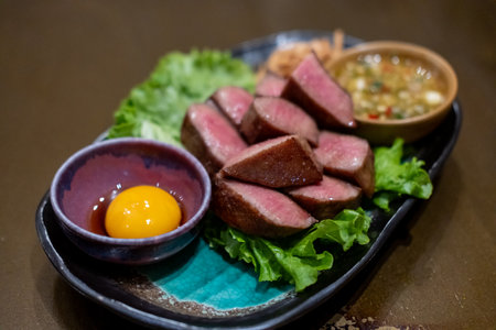 Grilled beef tongue served on plate with pickled egg yolk and sauceの写真素材