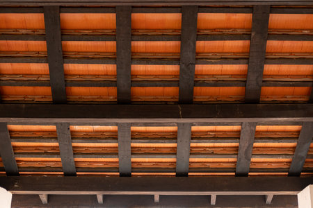 A view from inside a wooden pavilion, with dark wooden beams and terracotta roof tiles