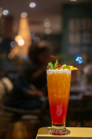 Close up view of cocktail, with cherry and sliced orange on top. On the table with bokeh background