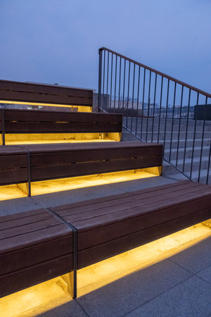 Wooden step and seating with lighting underneath, with metal handrail on the side