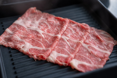 A close-up shot of sliced raw meat, arranged on a plate, ready to be cooked in a hot potの写真素材
