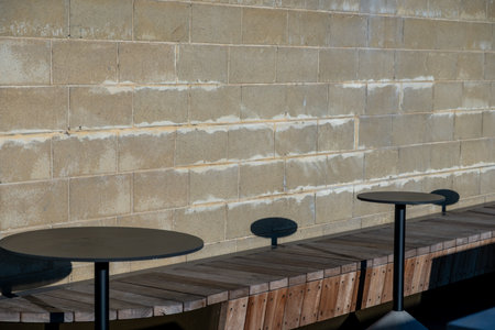 Wooden seating and metal tables next to the concrete wall