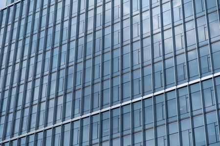 Close-up view of high-rise office building facade with reflection of blue skyの写真素材