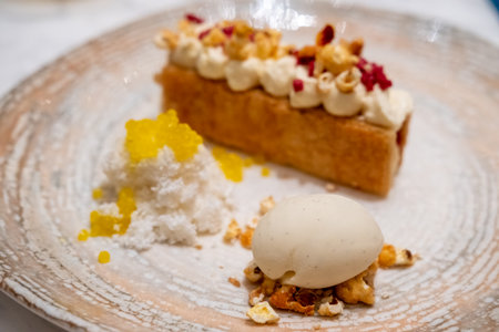 A tart with cream on top, with vanilla ice cream and crumble served on plate.の写真素材
