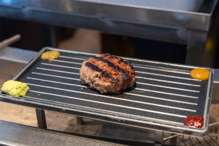 Grilled Hamburg, a patty of ground beef, on the plate with various sauceの写真素材