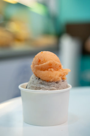 A cup of Gelato, Banana choc chip and tomato Ice-cream on the table with blur background.の写真素材