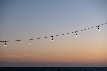 Light bulb, hanging string light with sunset beach view in the background