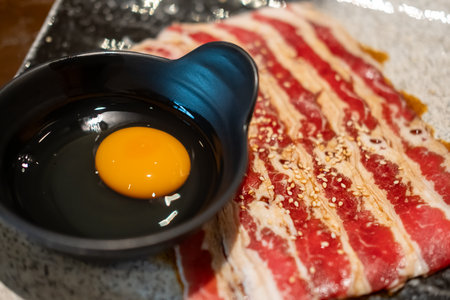 Close up of sliced brisket, raw meat, with a bowl of raw egg. prepared for cookingの写真素材