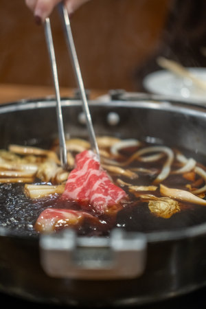 Chopstick holding sliced meat. hot potの写真素材