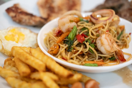 Spicy seafood spaghetti served on white plate, with french friesの写真素材