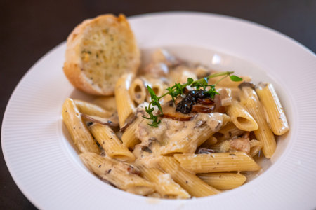 Penne Pasta with truffle sauce with bacon and garlic bread.の写真素材