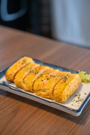 Tamagoyaki, a Japanese omelette made by rolling together several layers of fried beaten eggs, served on a plate.の写真素材