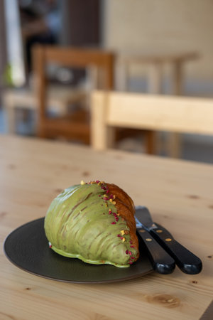 Croissant with pistachio served on plate, on the wooden table