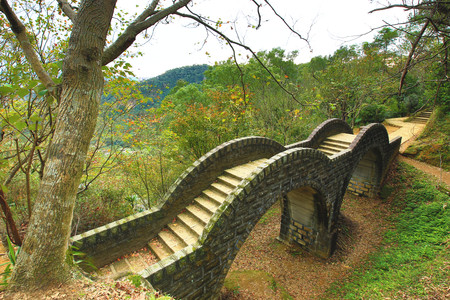 Arch Bridge among the valley with stairs and maple trees