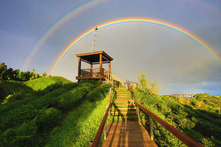 Beautiful landscape of amazing rainbows with wooden viewing deck and ladders at sunriseの写真素材