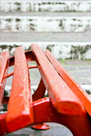 Close up of a red wooden seat with, on the back, old white stairs made of stones. This can  be a concept image with the implication of a choise. Choise between stay and go. Useful also  for relax and rest concept. Relax before start to go. Or relax at theの写真素材