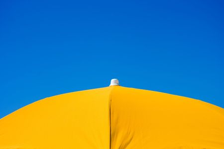 Orange beach umbrella over blue sky backgroundの写真素材