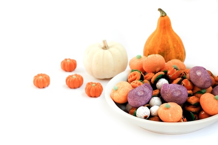 Dish full of halloween candy and two pumpkins on white background の写真素材