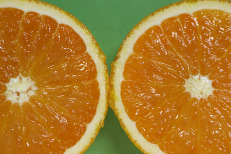 Slices of fresh orange on a green background close-upの写真素材