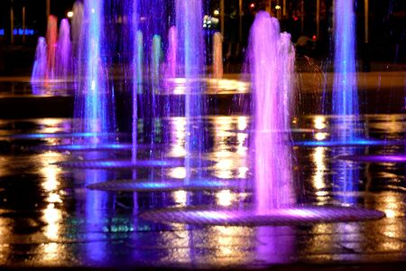 Fountain lit by coloured lights at nightの写真素材