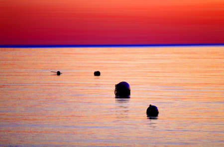 Sunset on the sea with two buoys in the water. Red and orange colors.