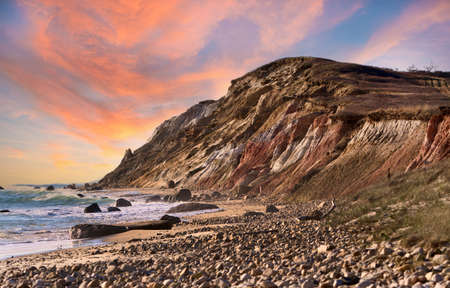 A panoramic shot of a rocky beach during a colorful sunset