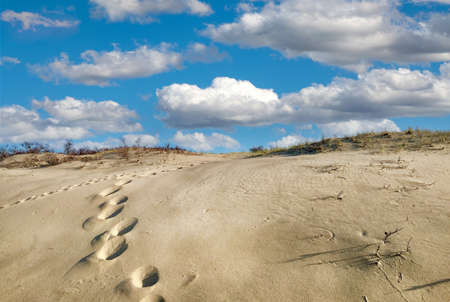 Footprints in the sand dunes on a sunny day with cloudsの写真素材