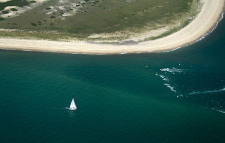Aerial view of a sailboat sailing in the sea with sand dunesの写真素材