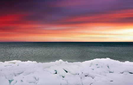 Beautiful winter landscape with frozen sea and colorful sky at sunset.の写真素材