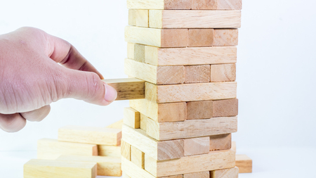 man hand pulling out the wooden block close upの写真素材