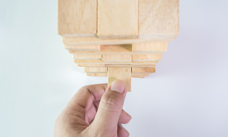 man hand pulling out the wooden block close up top viewの写真素材