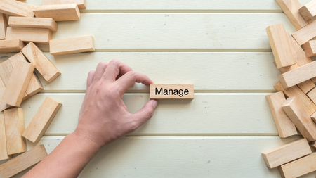 manage word written on wood block with hand holdの写真素材