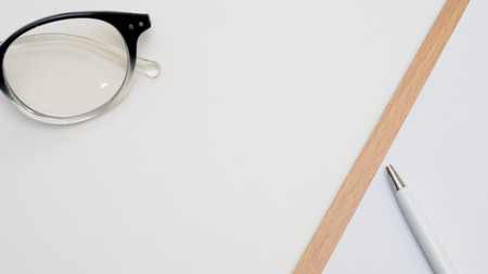 top view paper board with glasses and pen close up white backgroundの写真素材