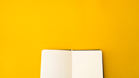 Office desk table Top view with notebook copy space yellow backgroundの写真素材
