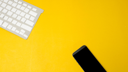 Office desk table Top view with keyboard  with smartphone  yellow backgroundの写真素材