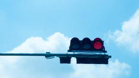 Traffic light with red light against the blue sky.